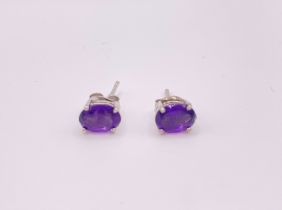 A pair of silver and amethyst stud earrings, set with oval-cut amethysts.
