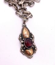 A silver and garnet pendant, of stylised form, set with a mixed oval-cut garnet, with applied gilt