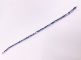 A silver and sapphire bracelet, set with mixed oval-cut blue sapphires, 18 cm long.