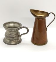 A vintage pewter drinking vessel with a brass and copper jug