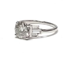 An 18ct white gold old-cut solitaire diamond ring set with baguette cut diamond shoulders. Solitaire