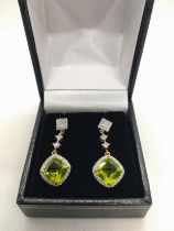 An 18ct yellow gold drop earrings set with cushion cut peridot and Round Brilliant Cut diamonds,
