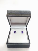 A pair of 18ct white gold studs set with oval amethyst fitted with rubber-capped butterflies, boxed.