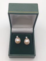 A pair of 9ct rose gold studs set with oval peach cultured pearls and 0.26ct diamonds, boxed.