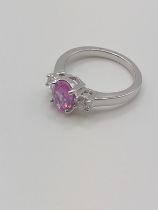 An 18ct white gold pink sapphire and diamond ring, the oval-cut sapphire of approximately 1.50