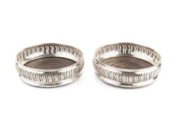 A pair of silver bottle coasters, with pierced and foliate carved decoration and turned hardwood