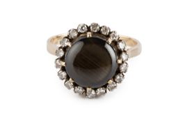 A black star sapphire and diamond cluster ring, the circular black star sapphire claw set within a