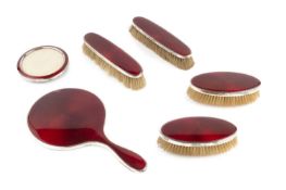 A silver and red enamel backed dressing table set, comprising hand mirror and two pairs of clothes