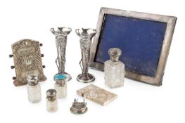 A pair of Edwardian silver spill vases, embossed with scrolling foliage and having three shaped