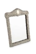 A late Victorian silver easel dressing table mirror, with arched top, repousse decorated with c