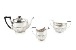 A late Victorian silver three piece tea service, of oval half-lobed design, the teapot with ebonised