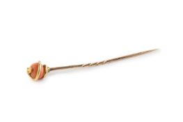 A coral stick pin, designed as a scrolled serpent enclosing a coral corallium rubrum bead,