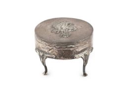 An Edwardian silver circular trinket box, the cover embossed with flowers, on shaped cabriole legs