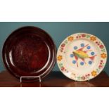 A large brown glazed pottery deep plate and a large deep glazed pottery painted plate