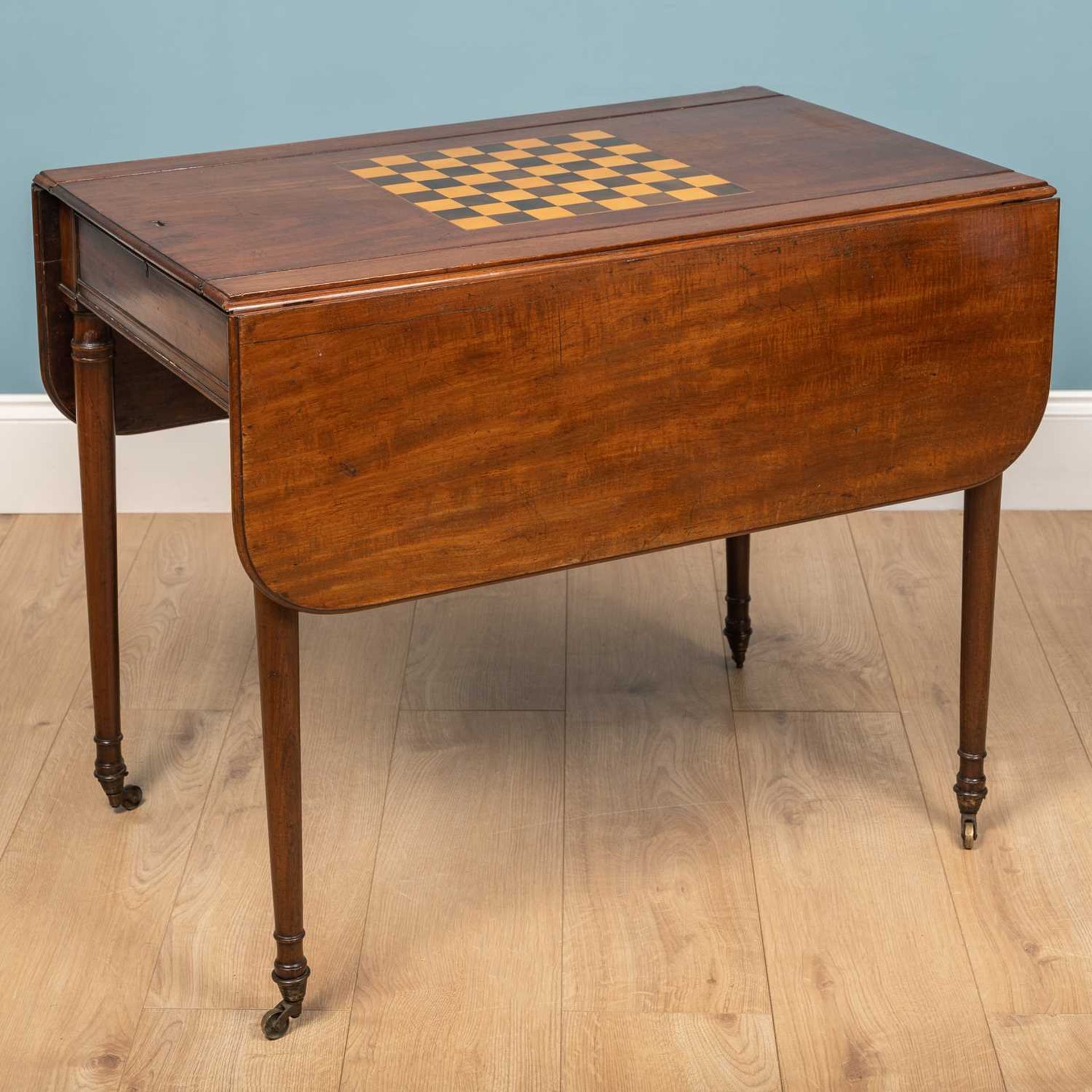 A George III mahogany games table with drop leaves