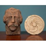 A carved sandstone head from Cockermouth, and a round carved stone element