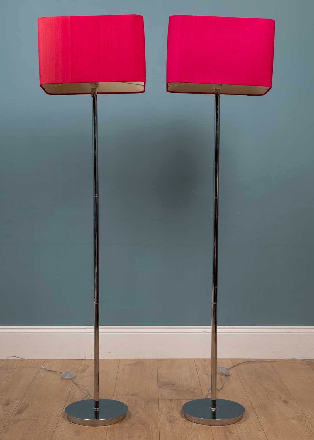 A pair of tall modern floor lamps with chrome stands and rectangular fuschia lampshades