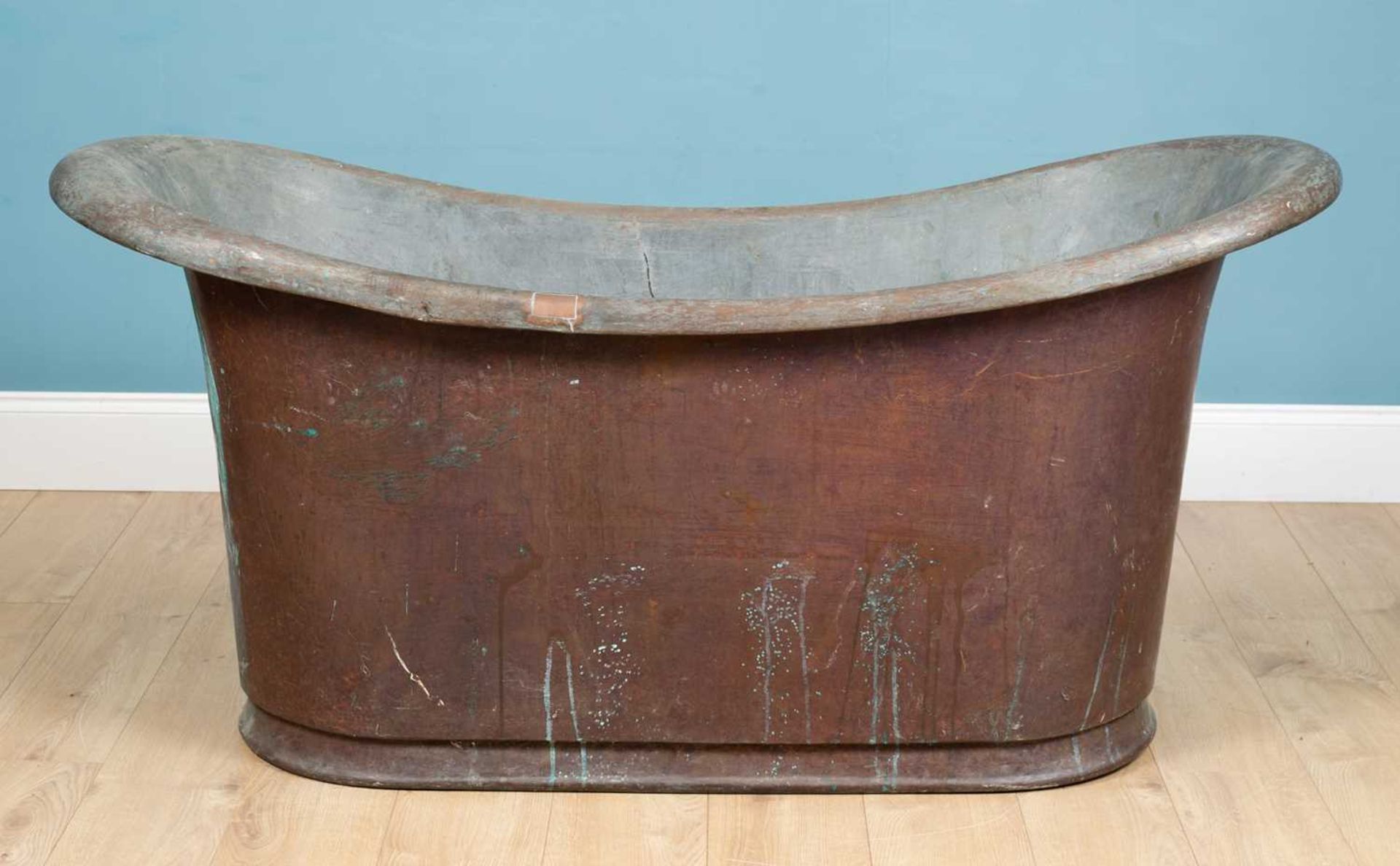 An antique 19th century roll top patinated copper bath