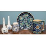 Three Iznik style pieces of pottery including a jug (12 x 13.5cm), a drinking cup (9 x 7cm) and a