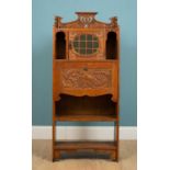 An Arts and Crafts bureau cabinet, circa 1910, carved oak with lion figure detail and green leaded