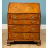 An 18th century-style walnut bureau, the fall front enclosing a fitted interior over four long