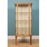 An early to mid 20th century oak display cabinet with bowed front and containing glass shelves,