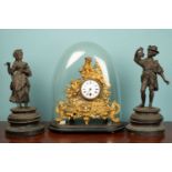 A gilded spelter mantle timepiece under a glass dome, ornately decorated with a female figure,