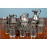 An assortment of pewter tankards and jugs, comprising of two lidded jugs and various tankards and