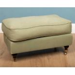 A rectangular green upholstered footstool on turned tapering legs terminating in brass casters, 79cm