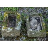 Two mossy and weathered stone trough planters