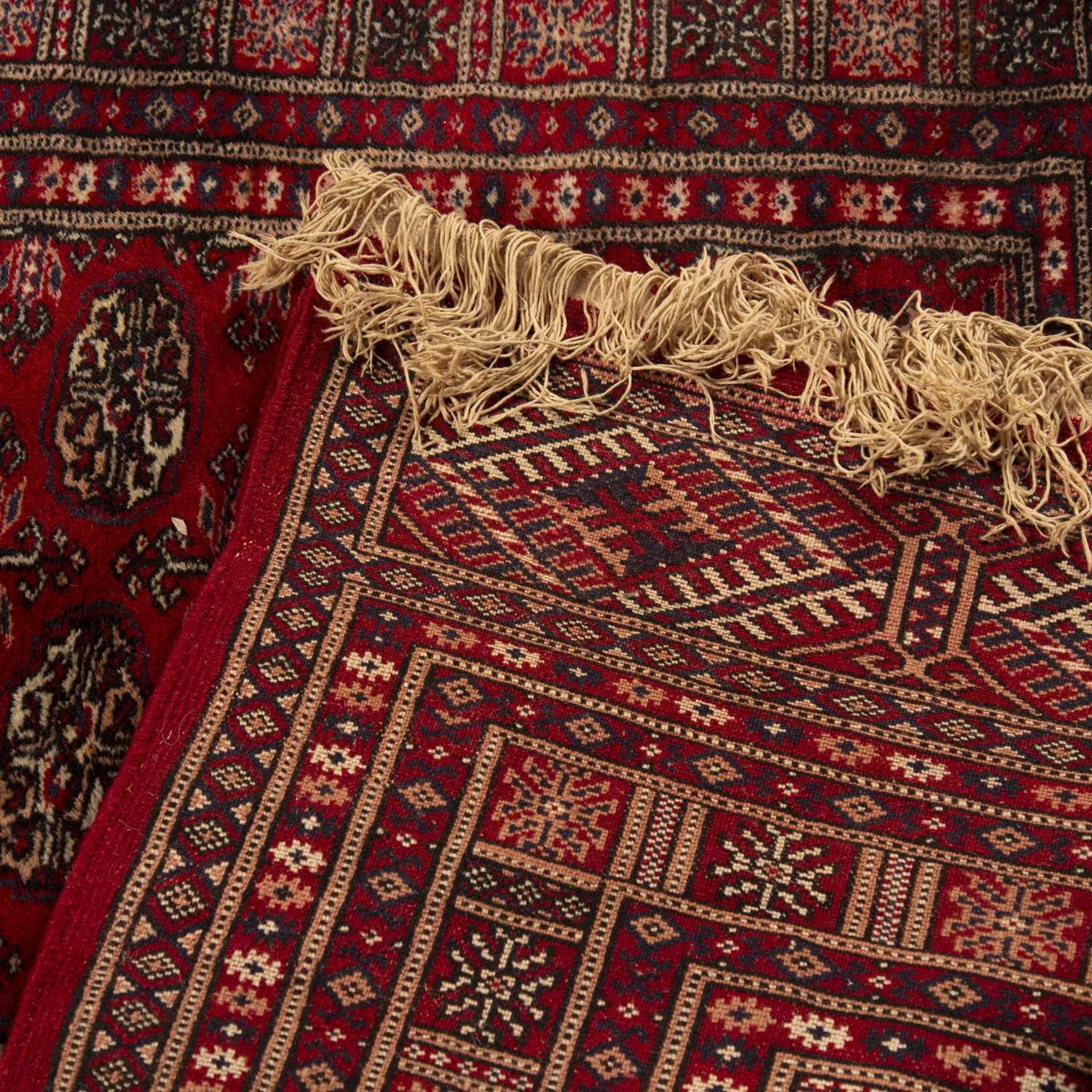 Red ground rug Pakistan, with a panel of elephant foot designs, 121cm x 172cmWith some light wear. - Bild 2 aus 2
