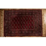 Red ground rug Pakistan, with a panel of elephant foot designs, 121cm x 172cmWith some light wear.