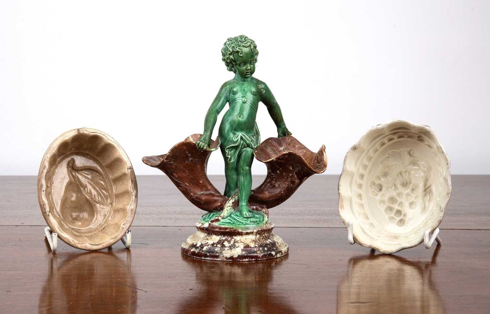 Creamware cherub spill vase the cherub holding onto two conch-style vessels, 18cm high, together