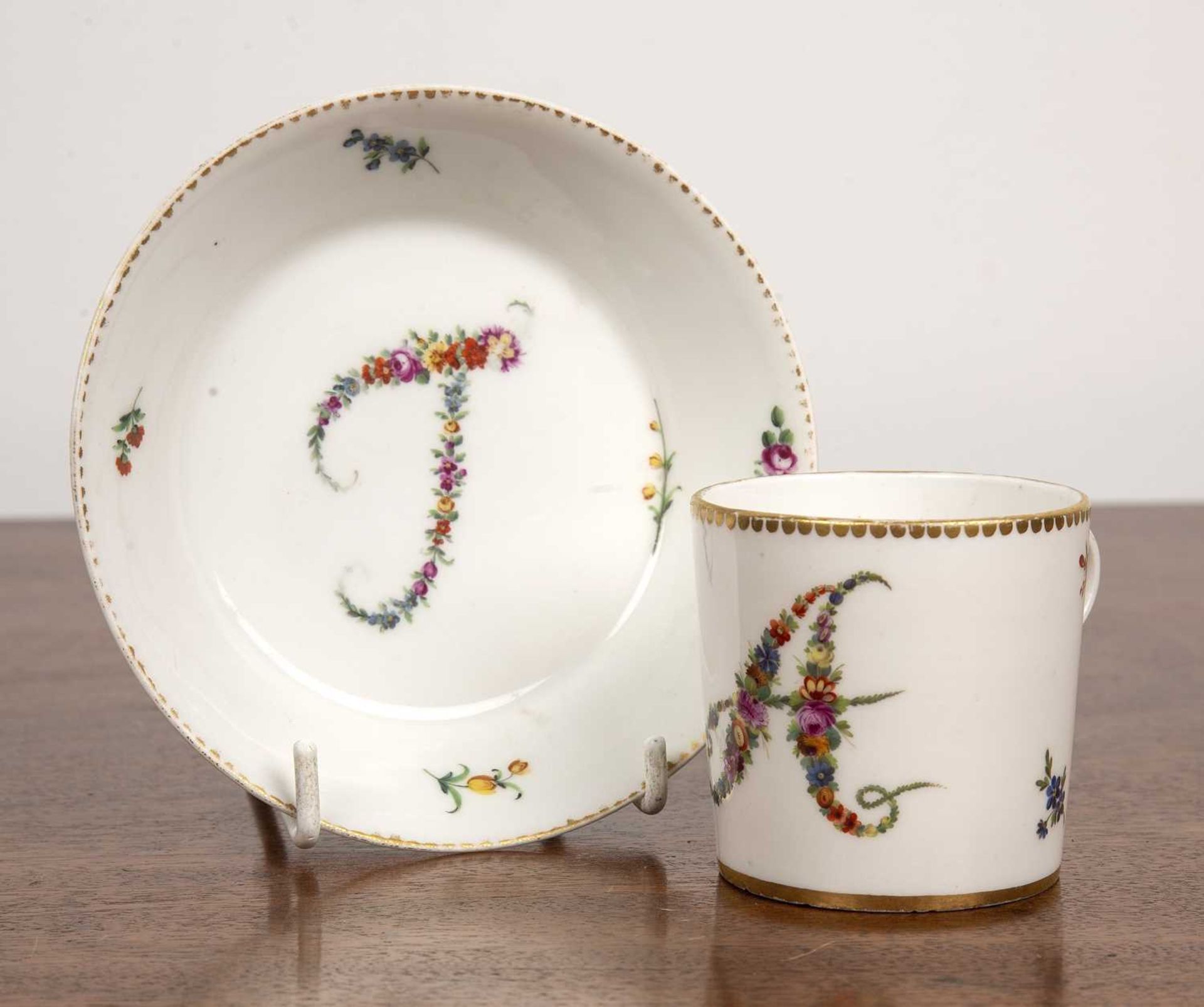 Porcelain coffee can and saucer French, circa 1800, painted with an 'A' and a 'T' in flowers,