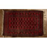 Red ground wool rug with geometric designs and stylised leaf border, 151cm x 89cm With light wear.