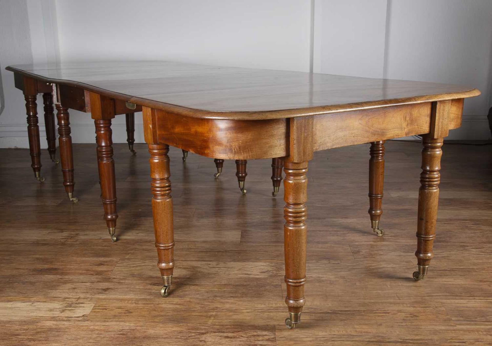 Mahogany D-end dining table 19th Century, with central drop-leaf on turned supports with brass