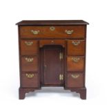 A George III style mahogany kneehole desk with a fitted top drawer above a central cupboard