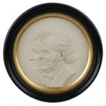 An early Victorian plaster portrait roundel of a lady and gentleman, with a gilded mount, ebonised