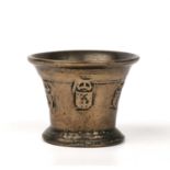 A 17th century bronze mortar with raised Heraldic decoration and a flared rim, 12.5cm diameter x 9.