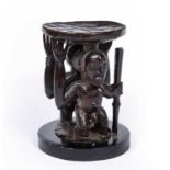 A 19th century African Yoruba carved wood stool with a male and female figure support, inset to a