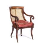 A Regency mahogany bergere library open armchair with a caned back and seat, scrolling arms, sabre