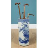 A porcelain umbrella stand together with two walking sticks, one cane and a riding crop