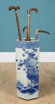 A porcelain umbrella stand together with two walking sticks, one cane and a riding crop