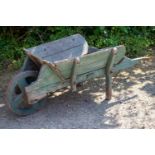 An old wooden green painted garden wheelbarrow