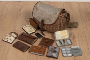 A wicker fishing creel containing various leather and tin wallets and boxes for fishing flies