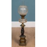 An antique brass and spelter oil lamp with glass shade and reservoir