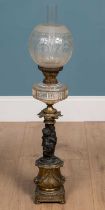 An antique brass and spelter oil lamp with glass shade and reservoir