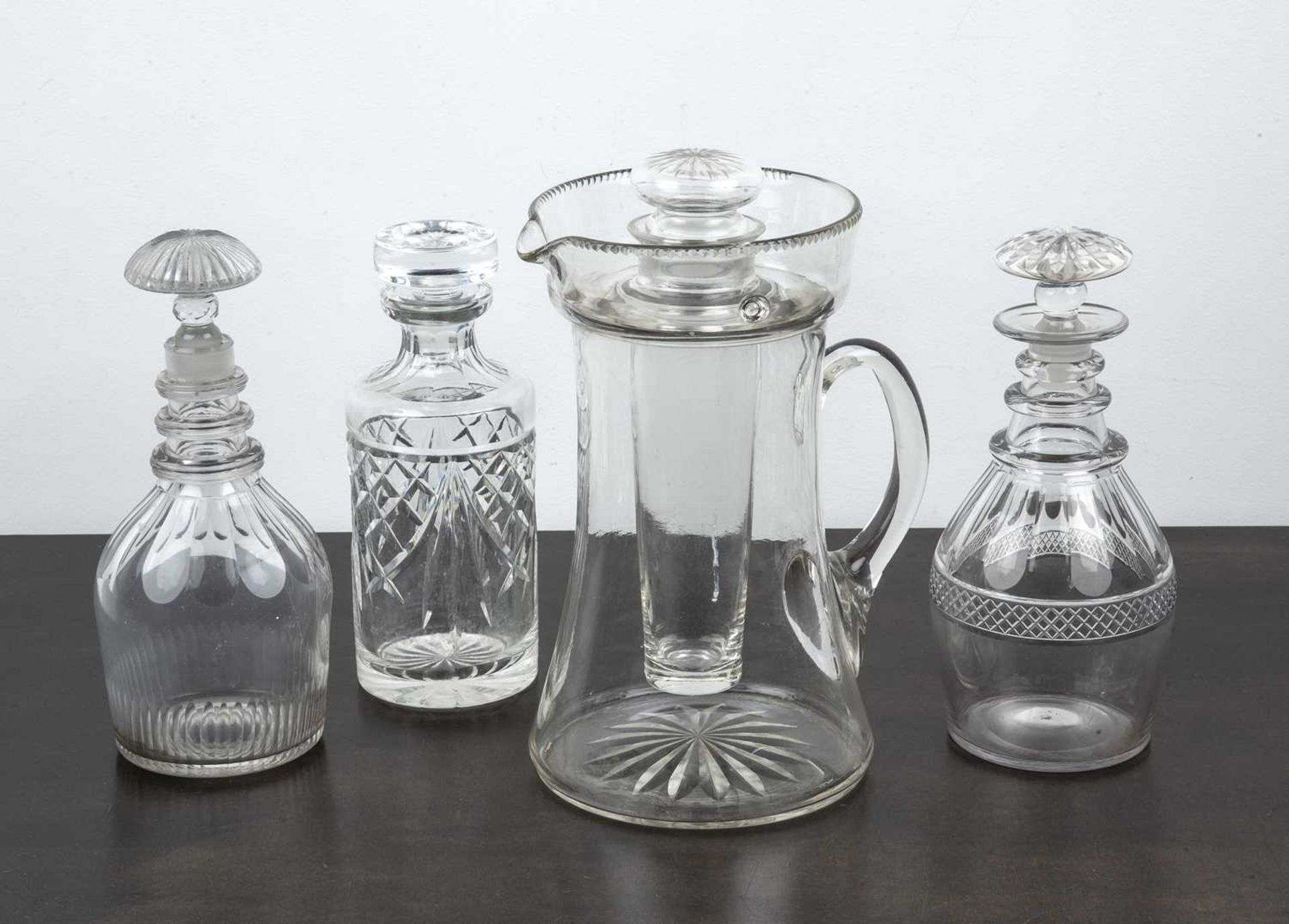 Collection of decanters including three decanters with lids and cut decoration, and a large glass