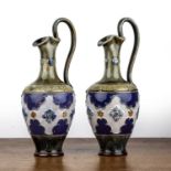 Royal Doulton Lambeth Pair of pottery ewers with blue banded and floral decoration on circular base,