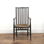 In the manner of Liberty and Co ebonised arm chair, with elongated vertical splats and rush seat,